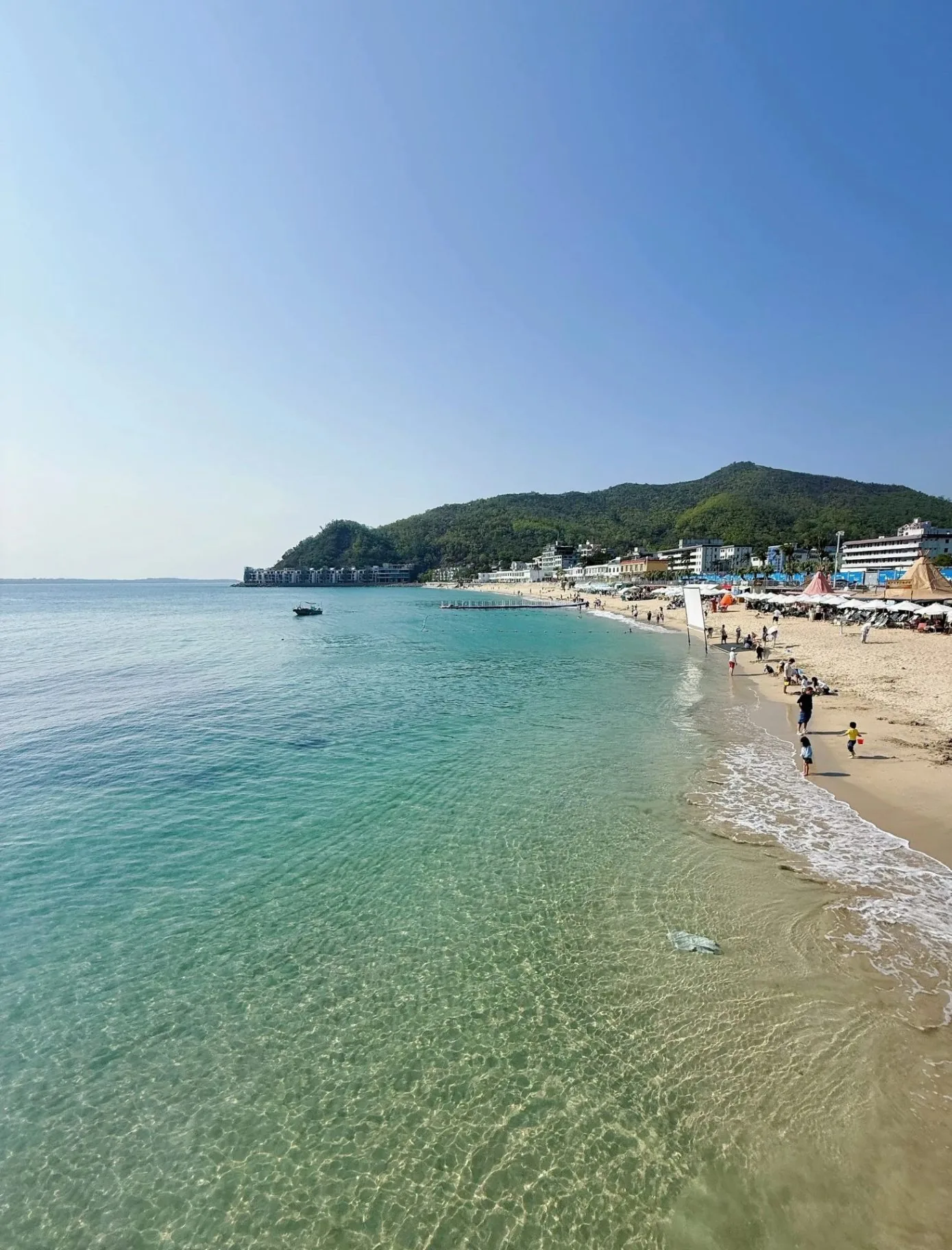 Families walking on a clean beach — the coastline a reusable metal straw helps protect
