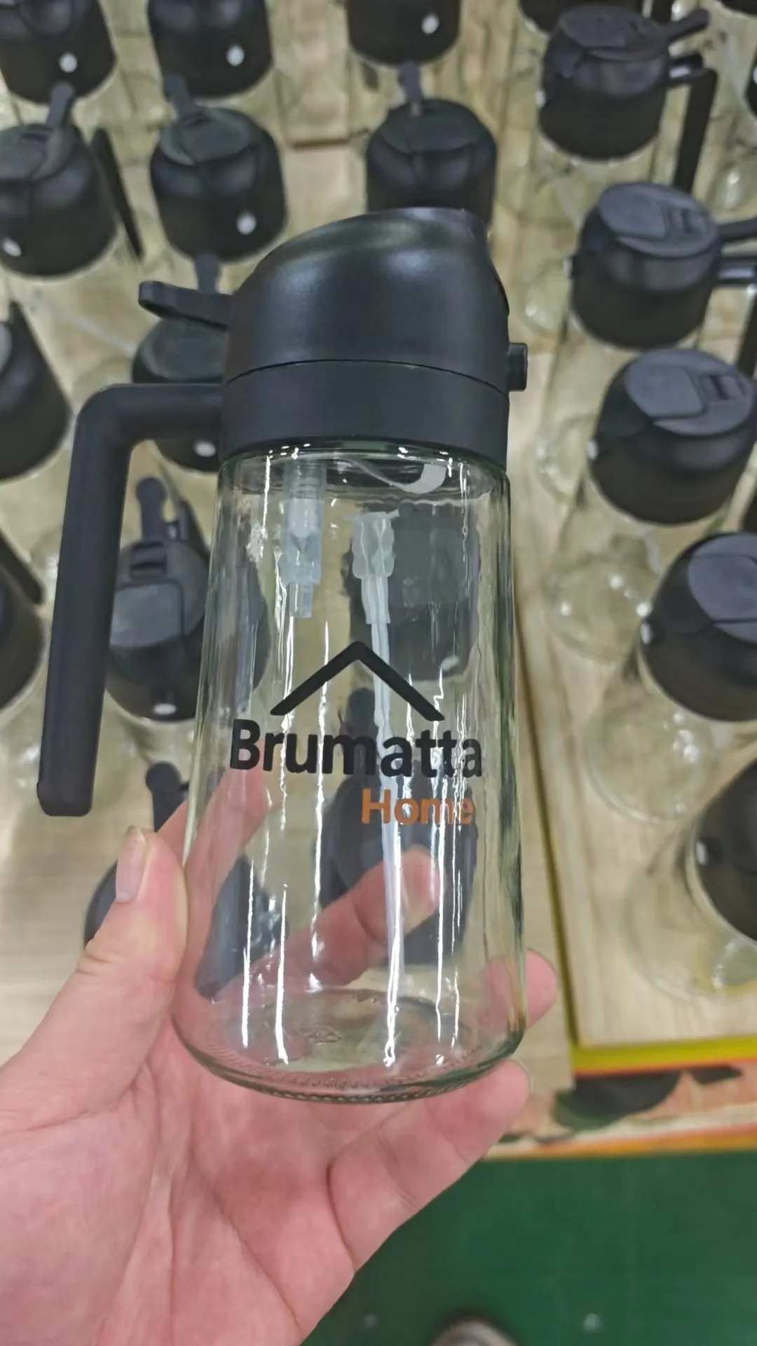 Private-label glass oil bottle with a custom logo printed, held on our Jieyang production floor